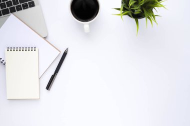 Beyaz ofis masasının üstünde klavye, defter ve kahve fincanı ve diğer ofis malzemeleri. İş ve finans kavramı. Çalışma yeri, boş kopya alanı olan düz uzanma.