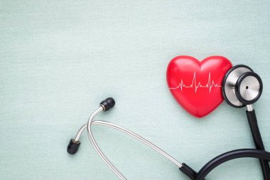 Siyah stetoskop, masa arkasını kontrol etmek için kardiyogramlı kırmızı kalp. Stetoskop ekipmanları kalp atışlarını tespit etmek için doktor tıbbi kullanımı. Dünya kalp günü. sağlık ve kardiyoloji kavramı.