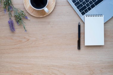 Ahşap ofis masasının üstünde dizüstü bilgisayarı, kahve fincanı ve ekipman ofis malzemeleriyle dolu defter var. İş ve finans kavramı. Çalışma yeri, boş kopya alanı olan düz uzanma.