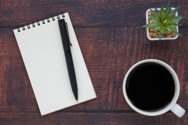 Boş sayfaları olan açık okul defterinin en üst görüntüsü, tahta masa arkaplanına not almak için kahve fincanı ve kalem. Düz yatış, yaratıcı çalışma alanı ofisi. Kopya alanı ile işletme eğitimi kavramı.