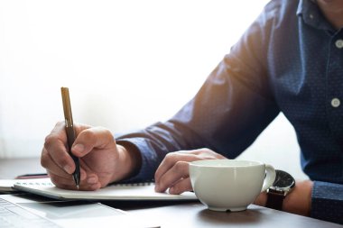 İş adamı elinde masa başındaki defter kağıdına kalem notu yazıyor. İşletme ve öğrenci işyeri, kopya alanı olan bir yazar. işletme çalışma ve öğrenme eğitim kavramı.