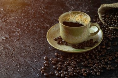Sabah içeceği menüsü için dumanlı sıcak sade kahve. Kahverengi seramik bardakta. Kahve çekirdekleri koyu grunge kırsal masa arka planında çuval içinde kavrulmuş. Kopyalama alanı olan düz.