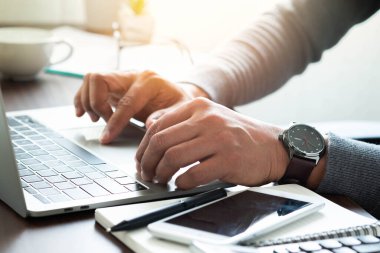 Bileğinde saatle bir adamın elinin yakın çekimi. Ofis masasındaki dizüstü bilgisayarın klavyesini kullanarak. Ofiste çalışan bir iş adamı. Yatırım finansmanı muhasebe kavramı.