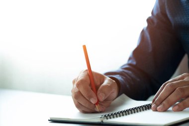 Not defterine ya da mektuba kalem ya da masa başındaki günlüğe not yazarak erkek eli yakın plan. Öğrenciler için iş yeri, kopya alanı olan bir yazar. işletme çalışma ve öğrenme eğitim kavramı.