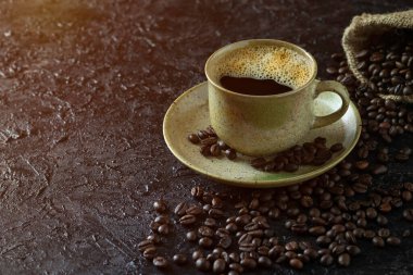 Sabah içeceği menüsü için sıcak sade kahve. Kahverengi seramik bardakta. Kahverengi kahve çekirdekleri koyu grunge kırsal masa arka planında çuval içinde kavrulmuş. Kopyalama alanı olan düz.