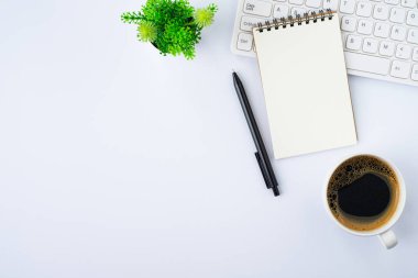 Üzerinde klavye, not defteri ve not defteri olan beyaz ofis masasının üstü, ekipman ofis malzemeleri olan kahve fincanı. İş ve finans kavramı. Çalışma yeri, boş kopya alanı olan düz uzanma.
