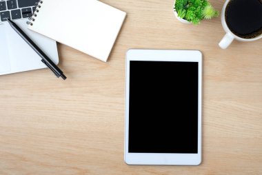 Tabletin üstündeki boş ekranın üst görüntüsü ahşap ofis masasında, dizüstü bilgisayarı, kahve fincanı olan siyah ekran. Çalışma alanı, ofis iş teknolojisi. Eğitim ve iş konsepti. düz yat