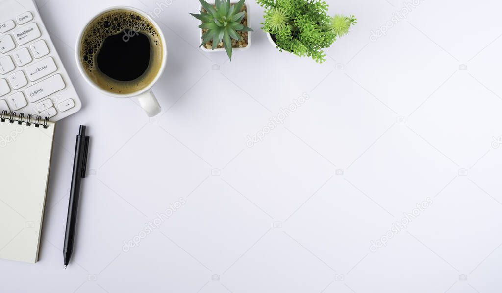 Top view above of White office desk table with keyboard, notebook and notepad, coffee cup with equipment office supplies. Business and finance concept. Workplace, Flat lay with blank copy space.