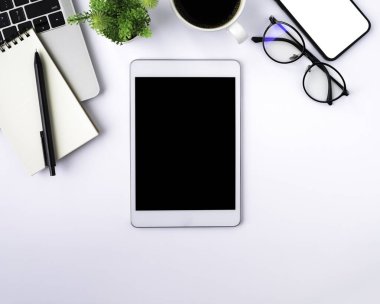 Tabletin üstündeki boş ekranın üst görüntüsü beyaz ofis masasındaki siyah ekranda defter, klavye, kahve fincanı. Çalışma alanı, ofis iş teknolojisi. Eğitim ve iş konsepti. düz yat