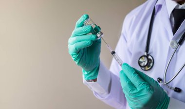 İlaç, elinde sıvı aşı olan şırınga, doktor. Aşı, kovid-19 virüsüne (koronavirüs) laboratuvarda aşı dozunda grip ilacı enjekte edilmesine direnir. Sağlık ve Tıp Konsepti.