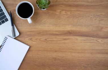Ahşap ofis masasının üstünde klavye, defter ve diğer ofis malzemeleriyle dolu kahve fincanı var. İş ve finans kavramı. Çalışma yeri, boş kopya alanı olan düz uzanma.