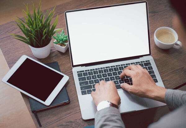 image of man hand using and typing keyboard of laptop computer notebook with blank monitor white screen display on table. Businessman working project. Business investment-finance accounting concept.