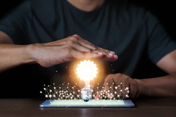 A Man hand holding light bulb and gear icon inside with network connection Innovative technology on tablet. Inspiration, brainstorming creative ideas for new innovations. Business technology creativity idea concept.