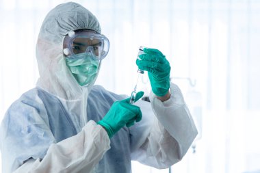Koruyucu giysili doktorlar hastanedeki karantina odasında CORONA VISRUS veya COVID-19 ile enfekte olan hastayı izliyor ve enjekte ediyor..