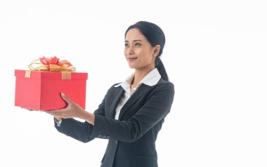 Güzel, gülümseyen, mutlu, siyah takım elbiseli, elinde kırmızı hediye kutusu olan genç bir kadın, izole edilmiş beyaz arka plandaki kameraya bakıyor..