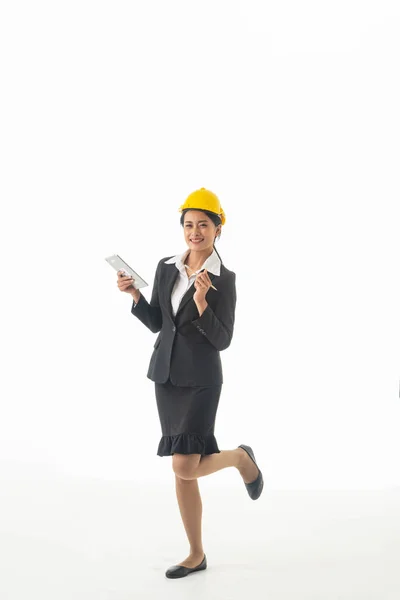 若いエンジニアの女性は黒のスーツと黄色の安全ヘルメットを保持ノートやタブレットを身に着けている隔離された白い背景 — ストック写真