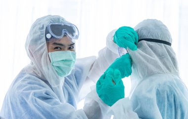 Koruyucu kıyafetli birkaç bilim adamı ya da doktor laboratuarda dinleniyor ve bir araya geliyorlar..