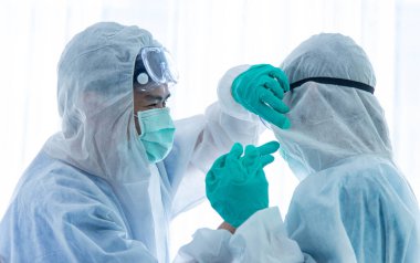 Koruyucu kıyafetli birkaç bilim adamı ya da doktor laboratuarda dinleniyor ve bir araya geliyorlar..