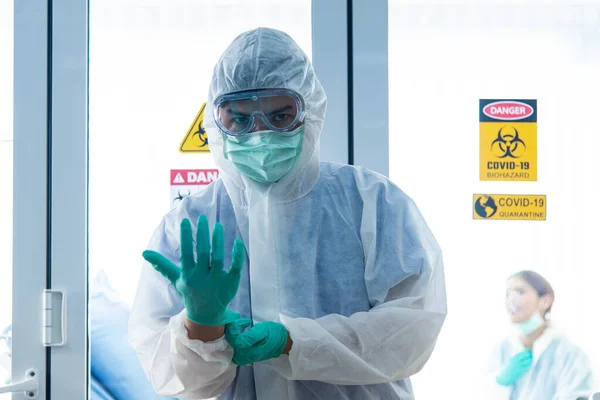 Doctors in protective suit wear medical rubber gloves looking at camera in front of CORONA VISRUS or COVID-19 quarantine room at the hospital.