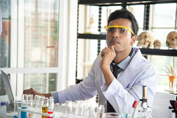 Young scientists or researchers wear eye glasses doing research in laboratory. Scientist working on computer and laboratory equipment.