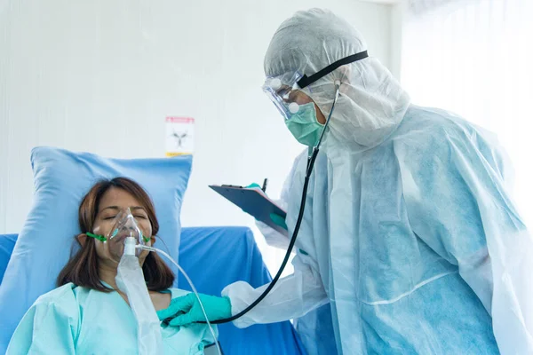 Koruyucu giysili doktorlar hastanın nabzını ve kan oksijenini kontrol ediyor. CORONA VISRUS veya COVID-19 virüsü taşıyan hasta hastanedeki karantina odasında..