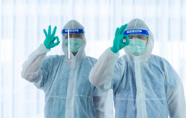 CORONA VISRUS veya hastanedeki karantina odasında COVID-19 yatak odası enfeksiyonlu yaşlı kadın hastaların yanında savaşmak için ayakta duran ve yüz maskesi takan iki tıbbi personel..