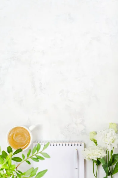 Bir fincan kahve, Eustoma, şam fıstığı yeşili, not defteri ve çimento kaplı kalem.