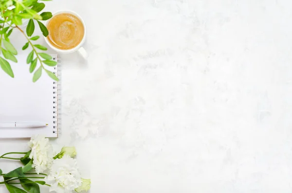 Bir fincan kahve, Eustoma, şam fıstığı yeşili, not defteri ve çimento kaplı kalem.