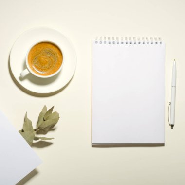 Bir fincan kahve, defter, kalem ve kurumuş çiçeklerle dolu bir işyeri. Model yap. Üst görünüm