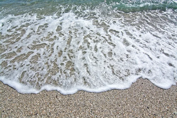 Ola espumosa golpea las rocas y conchas marinas playa primer plano — Foto de Stock