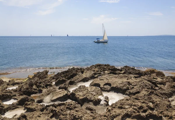 Pockets of sea salt in limestone rocks, sailboats on Palma bay. — Stock Photo, Image