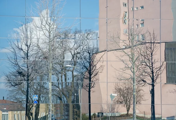 Edifícios e árvores refletidas na fachada de vidro moderna — Fotografia de Stock