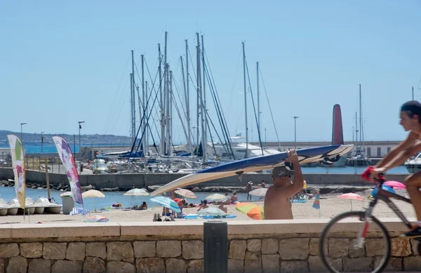 Street scene with surfer, masts and cyclist — Stock Photo, Image