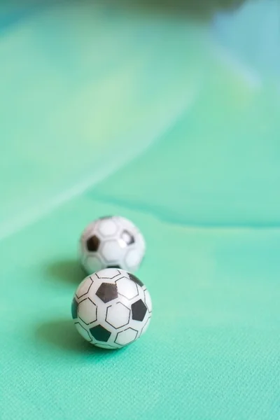Pelotas de fútbol de juguete sobre lienzo verde —  Fotos de Stock