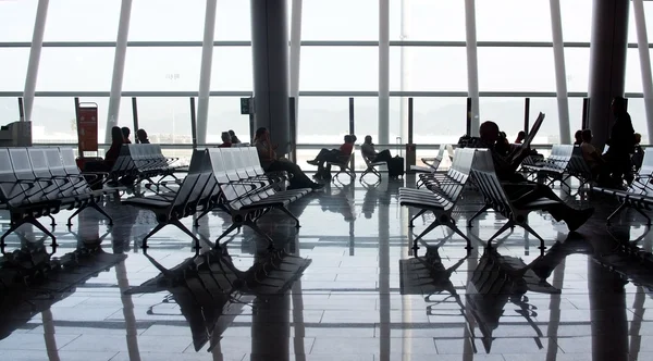 공항 내부 대형 유리 창과 빛나는 바닥 표면에 반영 하는 사람들 — 스톡 사진