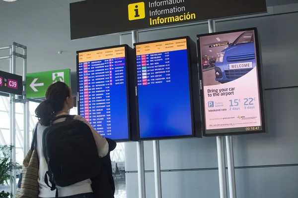 Woman reading departure information sign — Stock Photo, Image