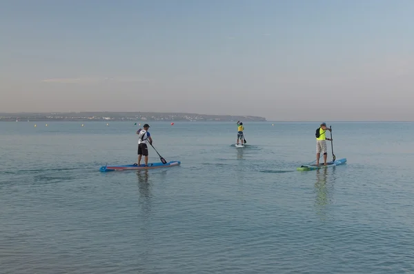 Tres surfistas de paddle board al amanecer —  Fotos de Stock