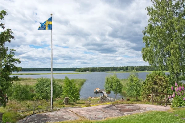 Svensk flagg på pole och liten båt i inloppet — Stockfoto