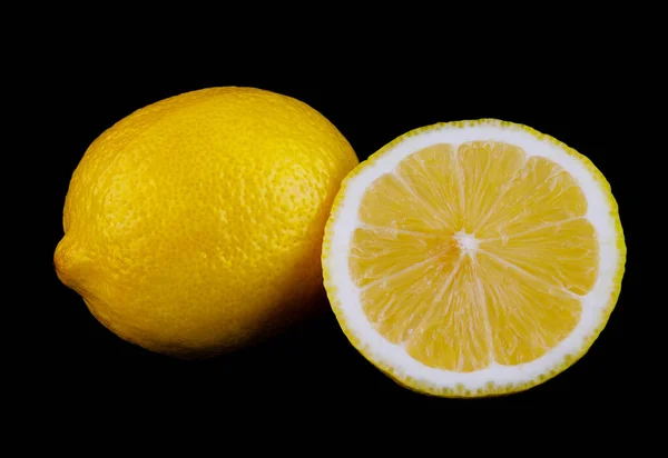 レモンとレモンの半分は黒い背景に隔離されている ストックフォト