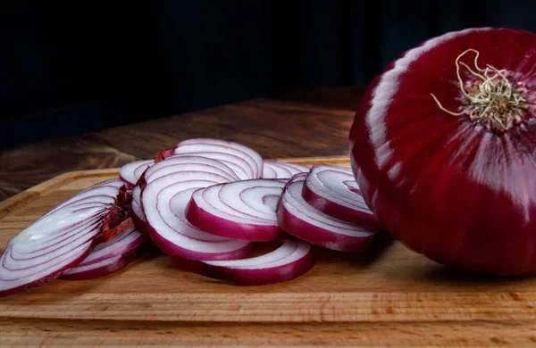 Whole bulb and chopped red salad onions on a wooden background.