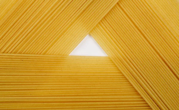 Thin pasta arranged in rows. Yellow italian pasta. Long spaghetti. Raw spaghetti wallpaper. Thin spaghetti. Food background concept.