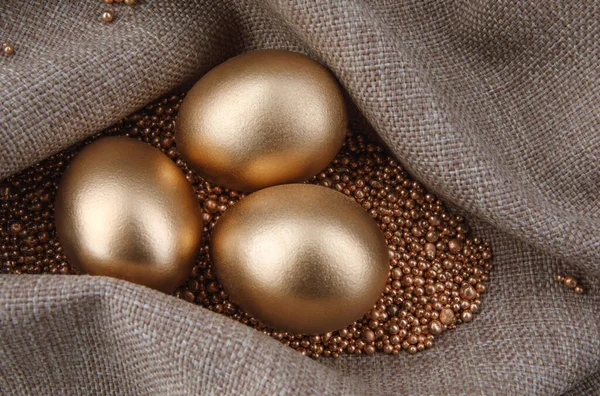 Three golden eggs on gold sand.