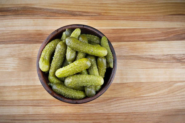 A cup of pickled cucumbers on a wooden background. Salted cucumbers.