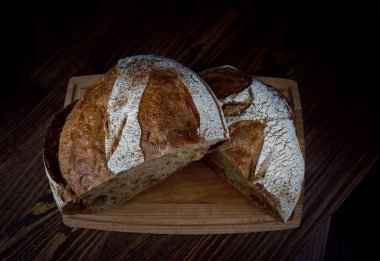 Bir somun çavdar ekmeği tahta bir kesme tahtasının üzerinde ikiye bölünmüş. Ev yapımı ekmek. .