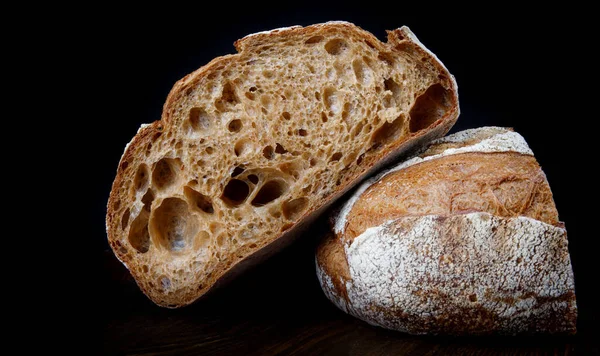 黑麦面包在黑色背景上切成两半的一块黑麦面包 — 图库照片