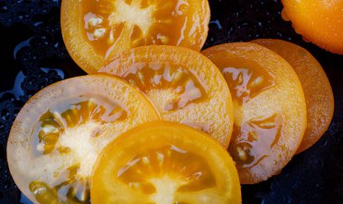 Siyah arka planda doğranmış sarı domatesler.