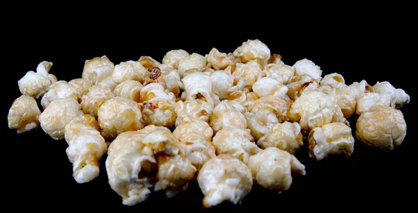 Crispy popcorn on a black background. Popcorn in caramel glaze.