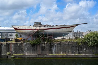 Okyanustan çıkmış bir yelkenli, tamir ediliyor ve bir tersanede bakılıyor.