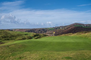 Galler kıyılarında golf sahasında, üzerinde bayrak olan el değmemiş bir golf sahası. Golf sahası, Three Cliffs Bay 'e bakan Pennard Golf Sahası.