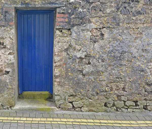 Porta de madeira azul em uma parede de pedra — Fotografia de Stock